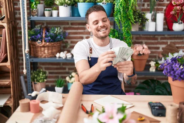 Young hispanic man florist smiling confident counting dollars at florist