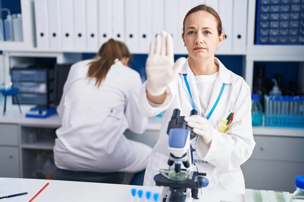 Blonde woman working on cruelty free laboratory with open hand doing stop sign with serious and confident expression, defense gesture