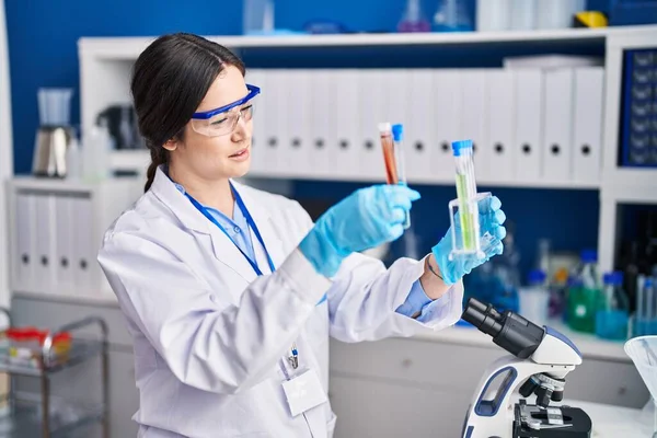 Young woman scientist holding test tubes at laboratory