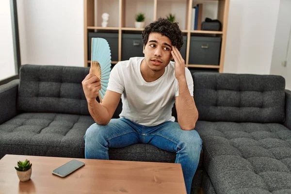 Jovem Hispânico Usando Ventilador Mão Sentado Sofá Casa — Fotografia de Stock