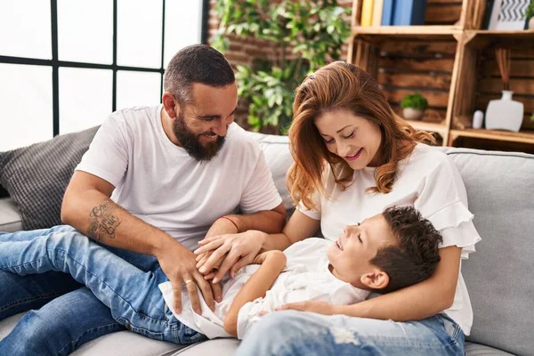Family doing tickle to son sitting on sofa at home