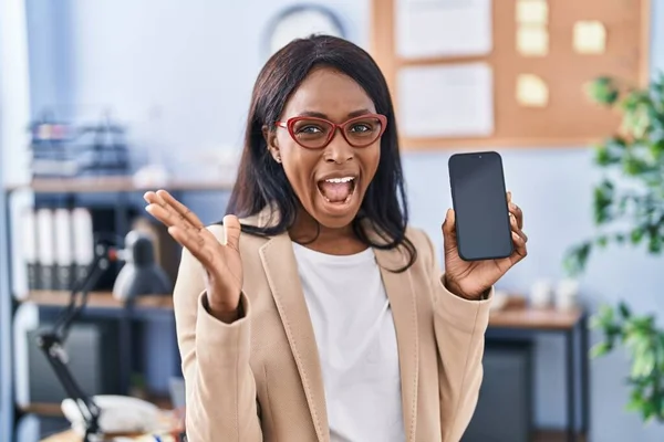 African Young Woman Holding Smartphone Showing Blank Screen Celebrating Victory — Stockfoto