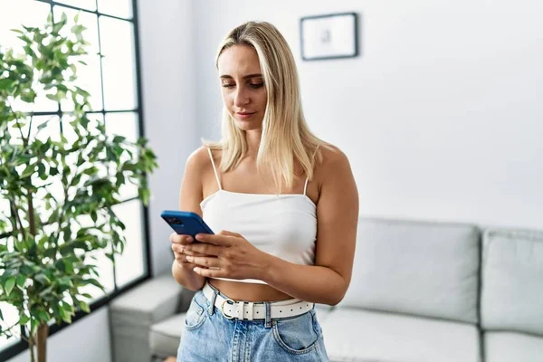 Nuori Blondi Nainen Joka Käyttää Älypuhelinta Kirjoittamalla Viestin Kotona Ajatteleva — kuvapankkivalokuva