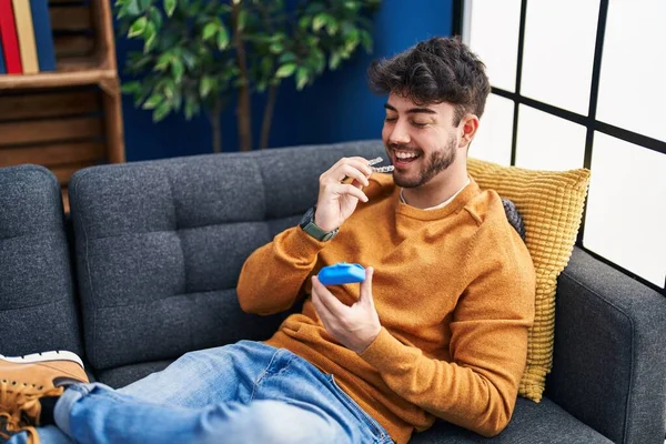 Young Hispanic Man Holding Invisible Aligner Sitting Sofa Home — Stockfoto