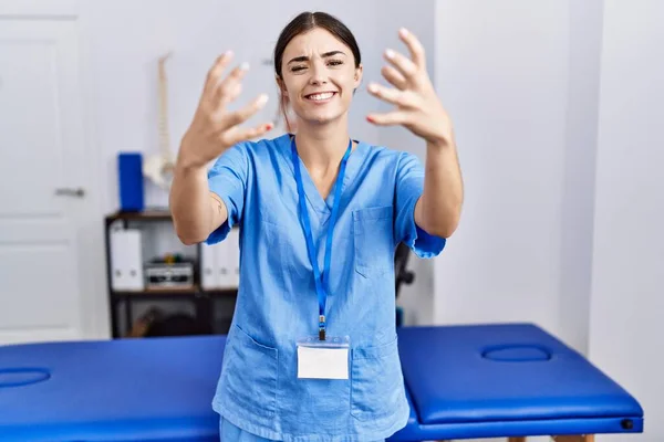 Giovane Donna Ispanica Uniforme Fisioterapista Piedi Alla Clinica Gridando Frustrato — Foto Stock