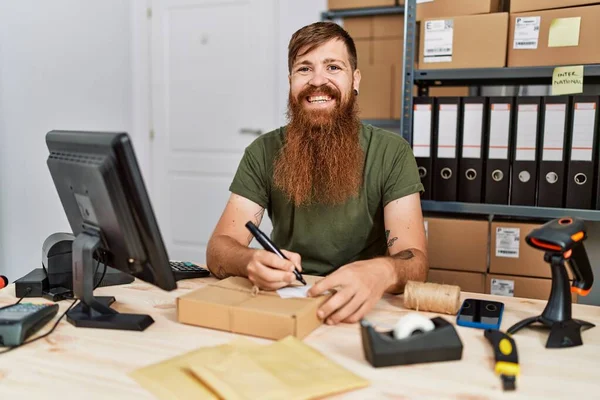 Young redhead man business worker prepare order package at office