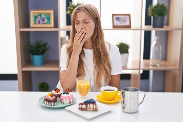 Young Caucasian Woman Eating Pastries Breakfast Bored Yawning Tired Covering — Fotografia de Stock