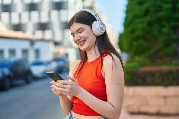 Junge Kaukasierin Lächelt Selbstbewusst Und Hört Musik Auf Der Straße — Stockfoto