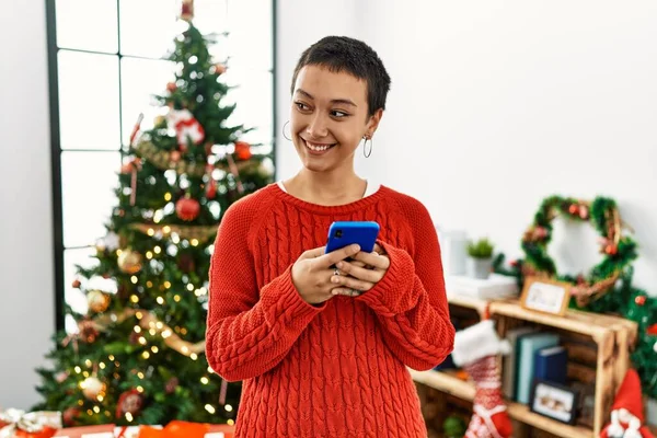 Jovem Hispânica Usando Smartphone Junto Árvore Natal Casa — Fotografia de Stock