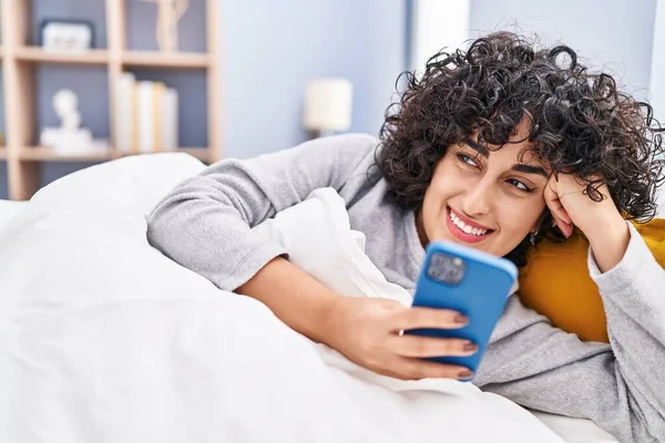 Νεαρή Γυναίκα Της Μέσης Ανατολής Χρησιμοποιώντας Smartphone Ξαπλωμένη Στο Κρεβάτι — Φωτογραφία Αρχείου