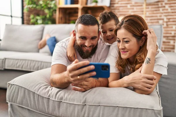 Family make selfie by smartphone lying on sofa at home