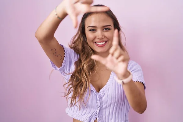 Молодая Латиноамериканка Стоящая Розовом Фоне Улыбающаяся Делая Рамку Руками Пальцами — стоковое фото