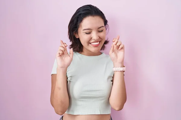 Hispanic Young Woman Standing Pink Background Gesturing Finger Crossed Smiling — Stock Photo, Image