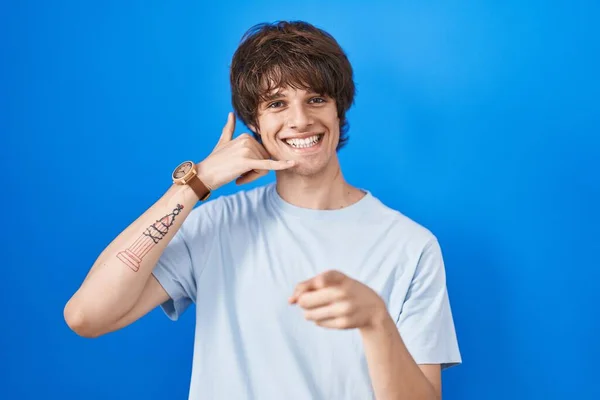 Іспанський Молодий Чоловік Стоїть Над Синім Фоном Усміхаючись Розмовляючи Телефону — стокове фото