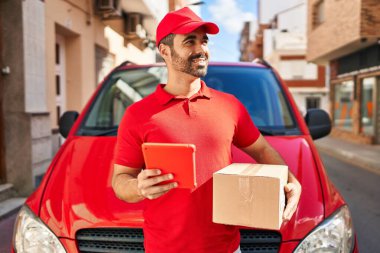 Genç İspanyol kurye sokakta dokunmatik ped paketi kullanıyor.