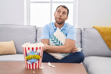 İspanyol adam evde televizyon seyrediyor. Kanepede oturuyor. Ağzı ve şaşı gözleriyle balık suratı yapıyor.. 