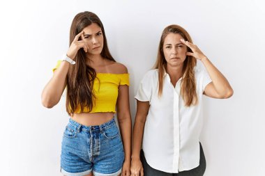 Anne ve kızı yalıtılmış arka planda yan yana duruyorlar. Alnındaki sivilceden mutsuzluğa işaret ediyorlar. Siyah noktalı çirkin bir enfeksiyon. sivilce ve deri problemi 