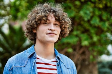 Genç İspanyol adam parkta gülümsüyor.