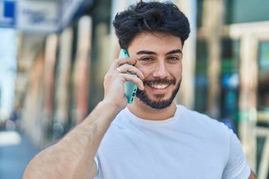 Genç İspanyol adam gülümsüyor. Kendine güveniyor. Sokakta akıllı telefondan konuşuyor.