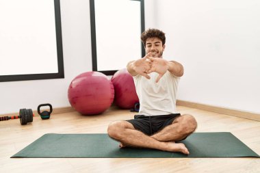 Genç İspanyol adam gülümsüyor spor merkezinde esniyor.