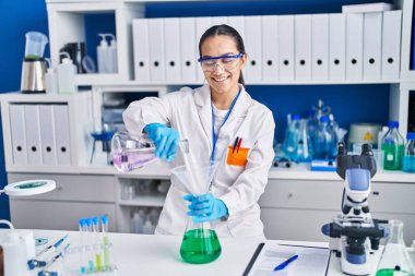 Laboratuvarda sıvıyı ölçen genç İspanyol bilim kadını.