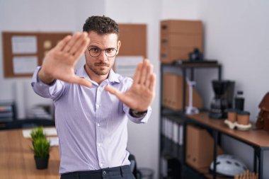 Ofisteki genç İspanyol adam elleri ve parmakları kullanarak çerçeve yapıyor. 