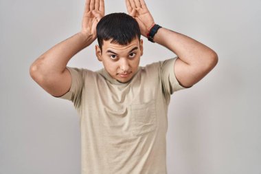 Young arab man wearing casual t shirt doing bunny ears gesture with hands palms looking cynical and skeptical. easter rabbit concept. 