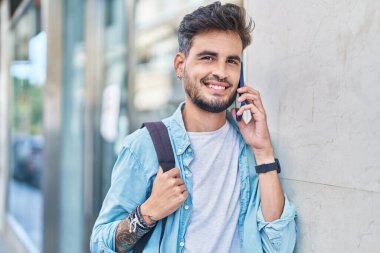 İspanyol asıllı genç bir öğrenci gülümsüyor. Akıllı telefondan konuşuyor.