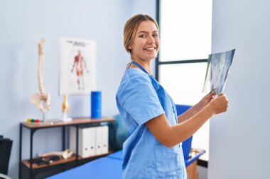 Young hispanic woman physiotherapist holding xray at rehab clinic