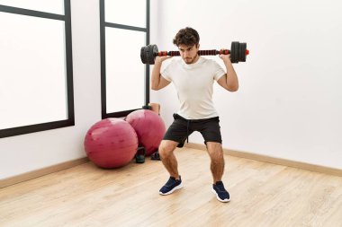 Spor merkezinde halterli genç bir İspanyol antrenman yapıyor.