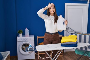 Çamaşırları katlanmış genç esmer kadın. Stresli ve hayal kırıklığına uğramış, şaşırmış ve kızgın bir yüzü var. 