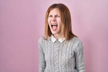 Güzel bir kadın pembe arka planda öfkeli ve kızgın bir şekilde öfkeli sinirli sinirli bağırıyor, öfkeyle bağırıyor. öfke ve agresif konsept. 