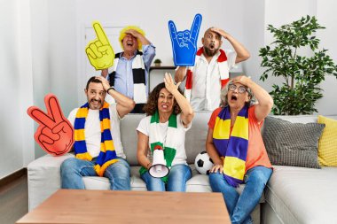 Evde futbol takımını destekleyen bir grup son sınıf öğrencisi kafa kafaya verip, şaşırmış ve sinirli bir yüz ifadesi takınıyorlar. 