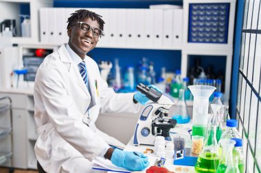 Laboratuardaki mikroskop raporunu kullanan Afrikalı Amerikalı bilim adamı.