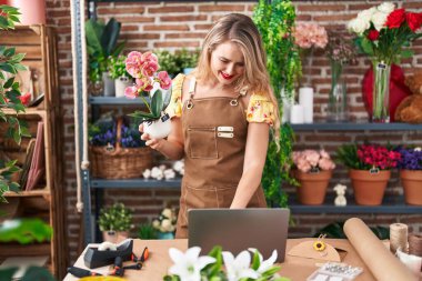Çiçekçide dizüstü bilgisayar kullanan güzel İspanyol bir çiçekçi.