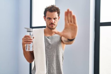 Spor kıyafetleri giyen genç İspanyol adam avuçlarıyla jestleri durduruyor, sinirli ve hayal kırıklığına uğramış bir ifade takınıyor. 