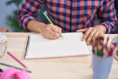 Young man artist drawing on notebook at art studio