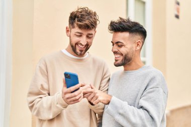 Young couple using smartphone standing together at street