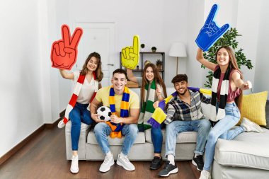 Evde futbol maçı izleyen ve destekleyen bir grup genç arkadaş..