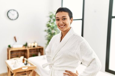 Bornoz giyen genç İspanyol kadın güzellik merkezine güvenerek gülümsüyor.