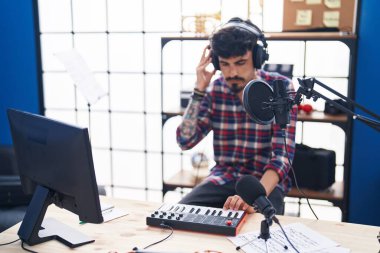 Young hispanic man musician having dj session at music studio
