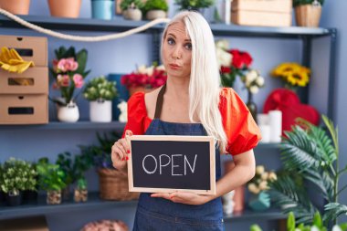 Caucasian woman working at florist holding open sign depressed and worry for distress, crying angry and afraid. sad expression. 
