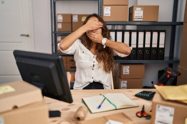 Küçük işletme şirketinde çalışan genç İspanyol bir kadın gözlerini ve ağzını elleriyle kapatıyor, şaşırmış ve şok olmuş. duygu gizleme 