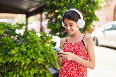Sevimli İspanyol kız sokakta müzik dinlerken kendinden emin gülümsüyor.