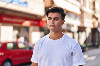 Latin kökenli genç adam ciddi bir ifadeyle sokağa bakıyor.
