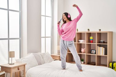 Genç, güzel İspanyol kadın yatakta şarkı söyleyip dans ediyor.