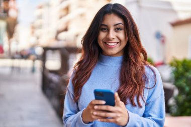 Sokakta akıllı telefon kullanan, kendine güvenen genç İspanyol kadın.