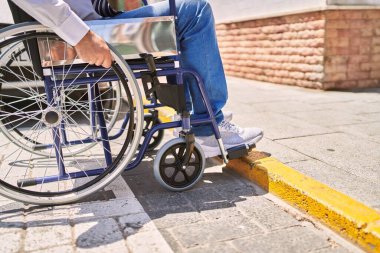Orta yaşlı, iş kıyafetleri giyen bir İspanyol sokakta tekerlekli sandalyede oturuyor.