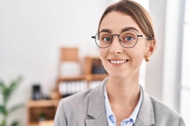 Kafkasyalı genç bir iş kadını ofiste kendinden emin gülümsüyor.