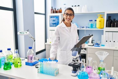 Laboratuvarda çalışan, bilim adamı üniforması giyen genç İspanyol kadın.